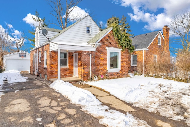 view of front of home with brick siding, an outdoor structure, a chimney, and a detached garage