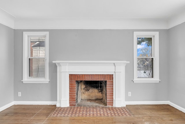 unfurnished living room with a fireplace, baseboards, and wood finished floors