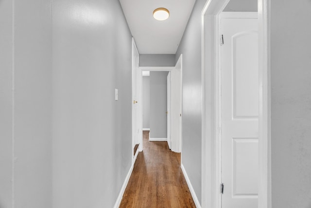 hallway featuring dark wood-style flooring and baseboards