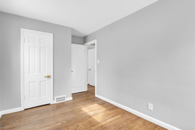 unfurnished bedroom with light wood-style flooring, visible vents, and baseboards