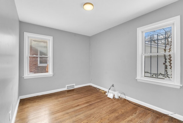 empty room with baseboards, visible vents, and wood finished floors