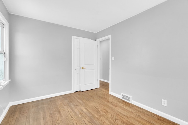 spare room featuring a healthy amount of sunlight, visible vents, baseboards, and wood finished floors