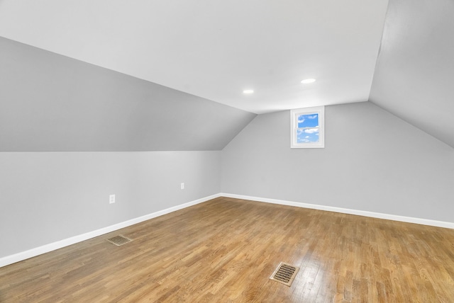 additional living space with lofted ceiling, visible vents, baseboards, and wood finished floors