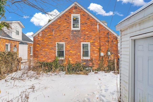 snow covered property featuring brick siding