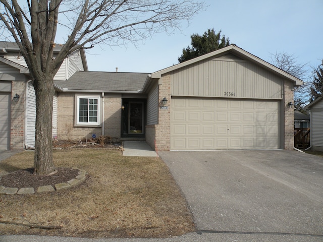 ranch-style home with an attached garage, driveway, a shingled roof, and brick siding