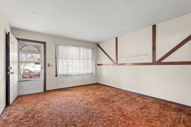 carpeted spare room featuring visible vents and baseboards