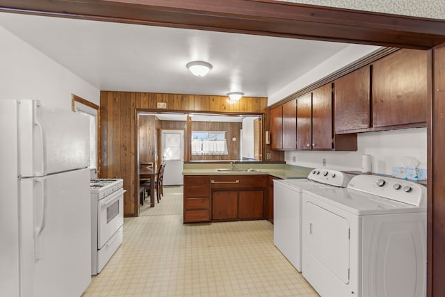 kitchen featuring light floors, white appliances, independent washer and dryer, and a sink