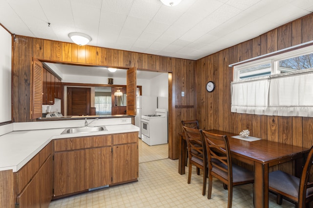 kitchen with light countertops, white range with gas stovetop, a healthy amount of sunlight, and a sink