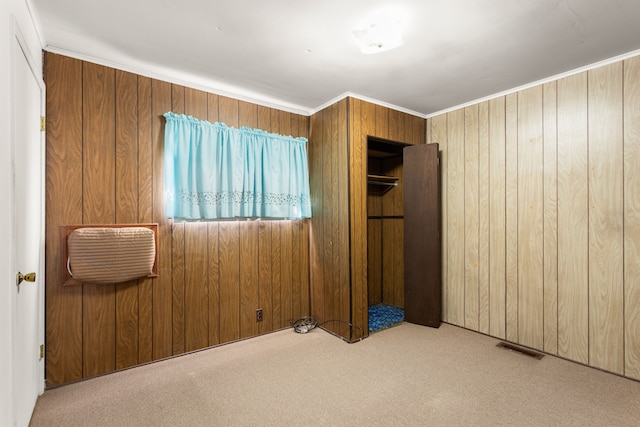 unfurnished bedroom featuring wood walls, carpet flooring, crown molding, and visible vents