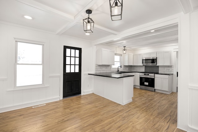 kitchen featuring light wood-style flooring, a peninsula, visible vents, appliances with stainless steel finishes, and beamed ceiling