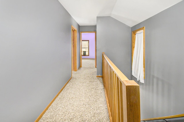 corridor featuring baseboards, lofted ceiling, an upstairs landing, and light colored carpet