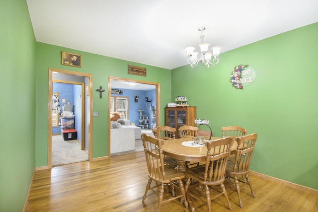 dining area with light wood-style floors, baseboards, and an inviting chandelier