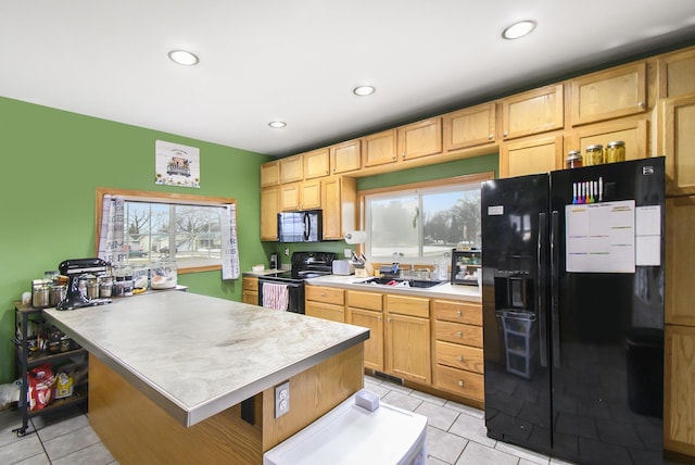 kitchen featuring plenty of natural light, a sink, black appliances, and light tile patterned floors