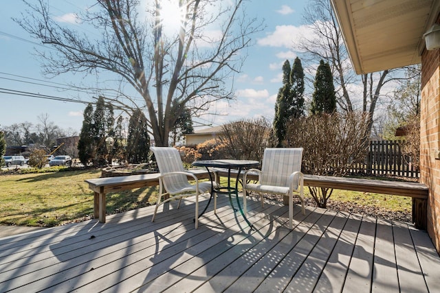 wooden terrace featuring outdoor dining area and a lawn