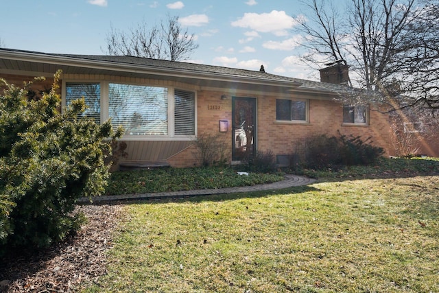 single story home featuring brick siding, a chimney, and a front lawn