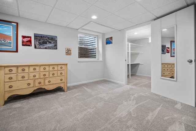 interior space featuring baseboards, a drop ceiling, carpet, a walk in closet, and recessed lighting