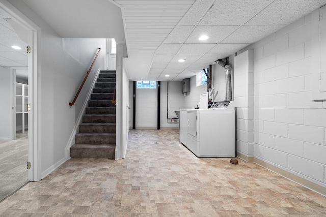 basement featuring a drop ceiling, recessed lighting, washer and dryer, stairs, and concrete block wall