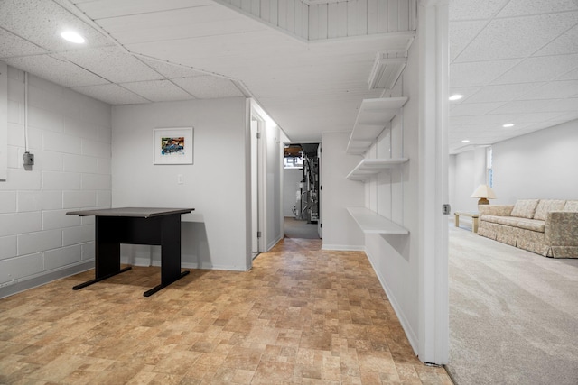 hallway with recessed lighting, a drop ceiling, concrete block wall, and baseboards