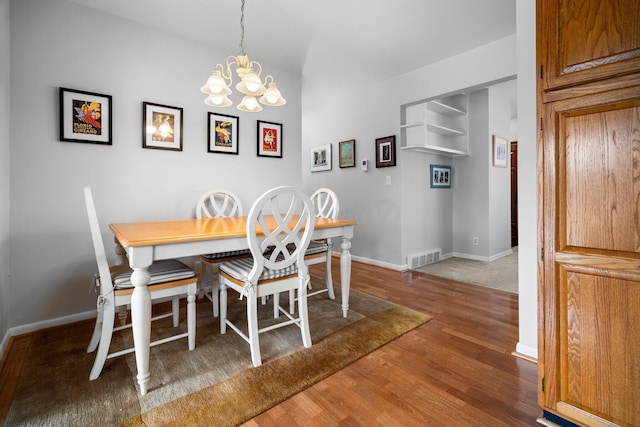 dining space featuring visible vents, baseboards, a chandelier, and wood finished floors