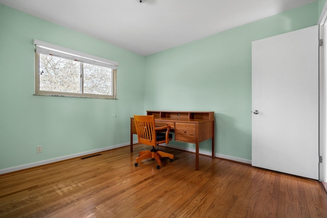 office area featuring baseboards, visible vents, and wood finished floors