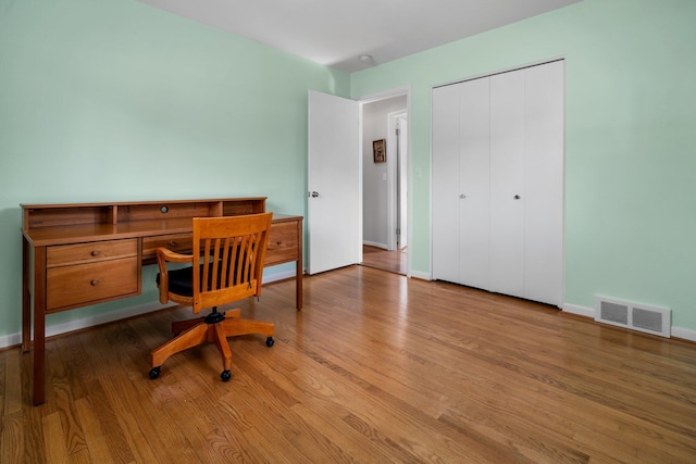 office space featuring baseboards, visible vents, and wood finished floors