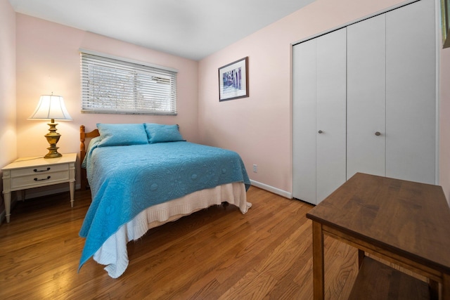 bedroom featuring light wood-style flooring, baseboards, and a closet