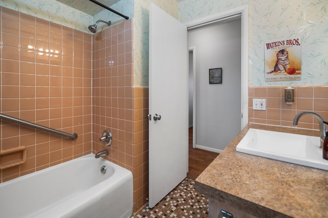 bathroom featuring tile walls, vanity, shower / bathtub combination, and wallpapered walls