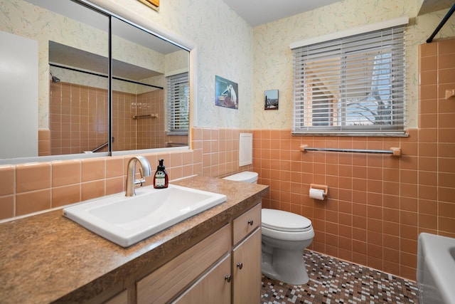 full bath featuring toilet, wallpapered walls, tile walls, and a wainscoted wall