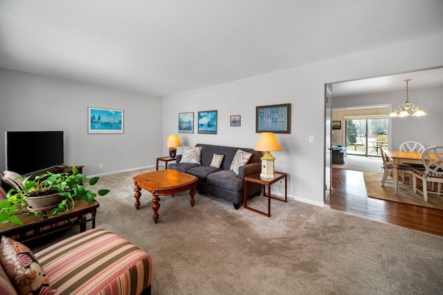 living room featuring carpet floors, baseboards, and a chandelier