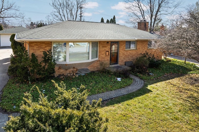 ranch-style home with brick siding, a chimney, a shingled roof, and a front yard