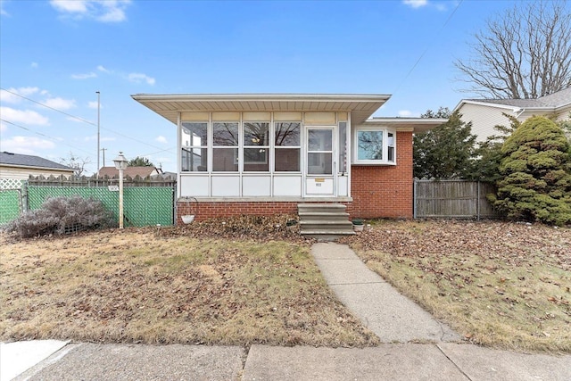 bungalow-style home featuring entry steps, brick siding, and fence