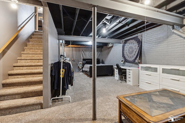 finished basement featuring brick wall, carpet, and stairs