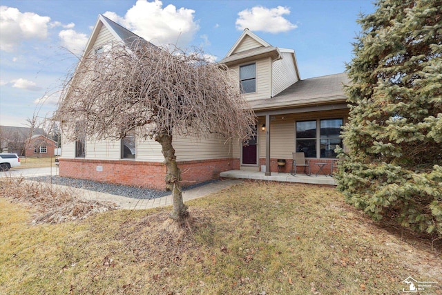 view of front of house featuring brick siding, a porch, and a front yard