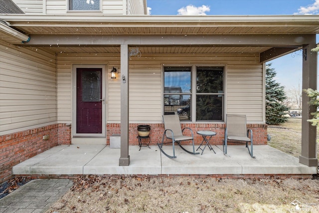 entrance to property with a porch and brick siding