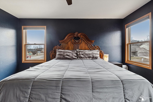 bedroom featuring a textured wall, multiple windows, and a ceiling fan