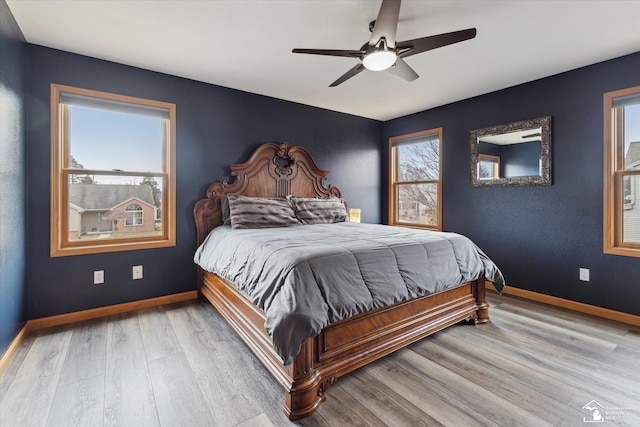 bedroom featuring multiple windows, baseboards, and wood finished floors