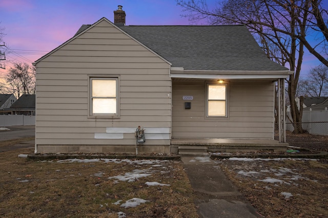 rear view of house featuring roof with shingles, a chimney, and fence