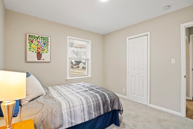 carpeted bedroom with a closet and baseboards