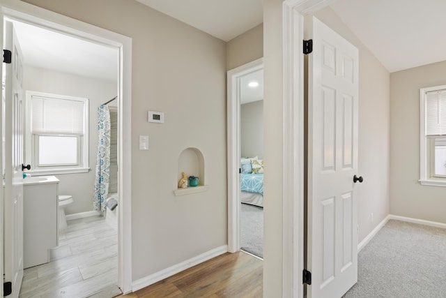 hallway with plenty of natural light, wood finished floors, and baseboards