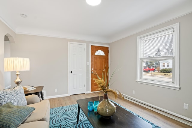 living area with ornamental molding, wood finished floors, arched walkways, and baseboards