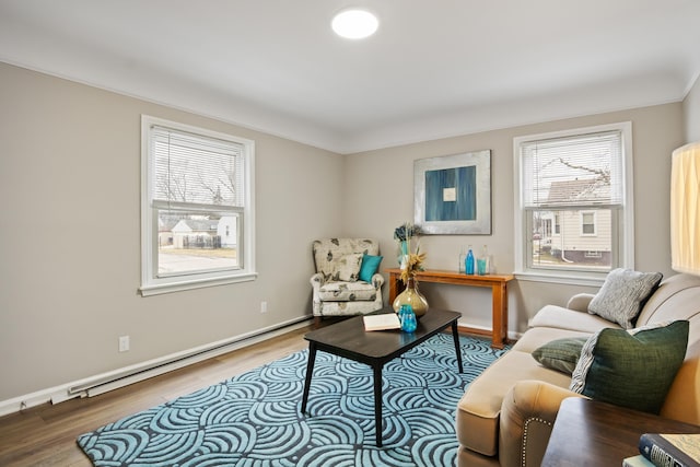 living area featuring a healthy amount of sunlight, a baseboard heating unit, baseboards, and wood finished floors