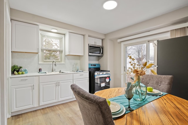 kitchen featuring plenty of natural light, stainless steel appliances, light wood-type flooring, and a sink