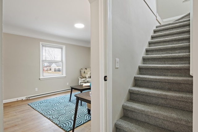 staircase with wood finished floors, baseboards, and baseboard heating