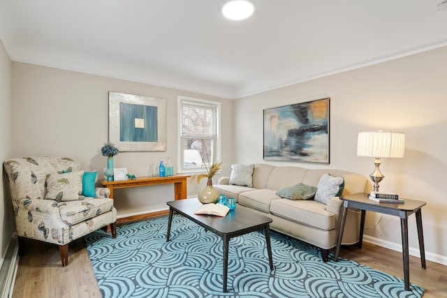 living area featuring crown molding, baseboards, and wood finished floors