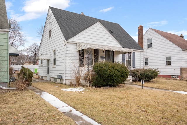 bungalow-style house with a shingled roof and a front lawn