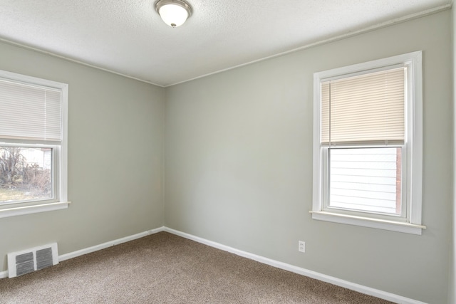 carpeted empty room with visible vents, a textured ceiling, and baseboards