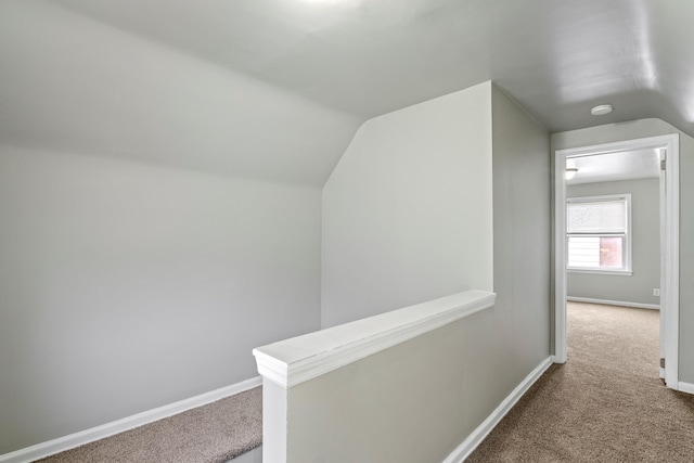 corridor with vaulted ceiling, carpet, an upstairs landing, and baseboards