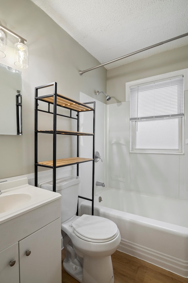 bathroom with a textured ceiling, toilet, wood finished floors, vanity, and  shower combination