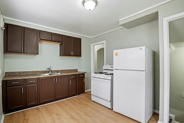 kitchen featuring dark countertops, light wood-style flooring, a sink, dark brown cabinetry, and white appliances