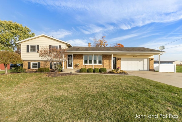 split level home featuring a garage, concrete driveway, fence, a front lawn, and brick siding